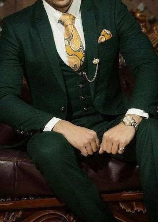Man in a dark green suit with a patterned tie sitting on a leather chair.